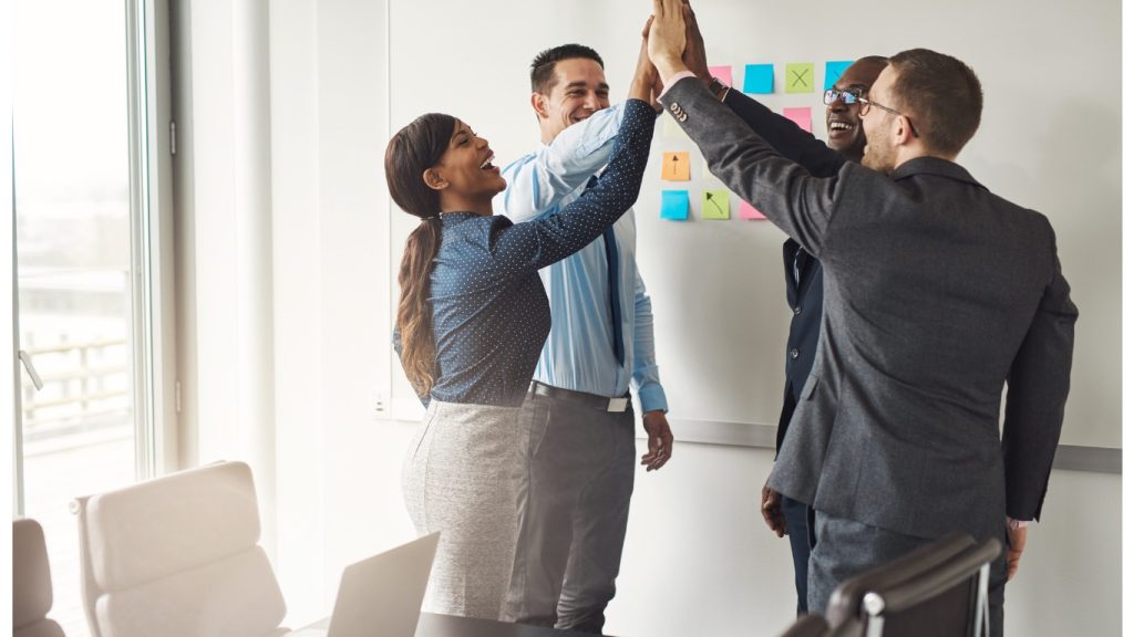 Team di professionisti che festeggia un successo durante una riunione di lavoro.